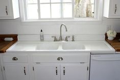 a white kitchen sink sitting under a window