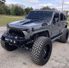 a gray jeep parked on top of a gravel road