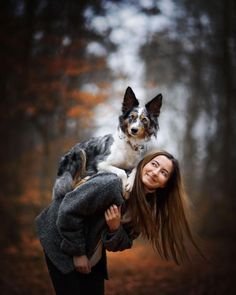 a woman is holding a dog in the air while she looks up at it's owner