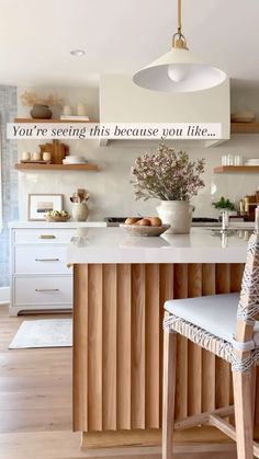 a white kitchen with an island and wooden shelves on the wall, along with a quote above it that reads you're seeing this because you like