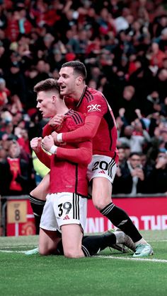 two soccer players are congratulating each other on the field in front of an audience