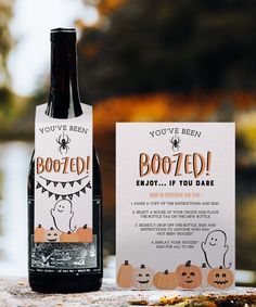 a bottle of boozed wine next to a card and some pumpkins on the table