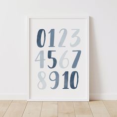 a white framed poster with numbers on it in front of a wall and wooden floor