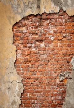 an old brick wall with peeling paint and chipping off the top, showing cracks in it