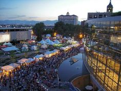 a crowd of people standing around tents in the middle of a city at night time