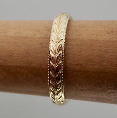 a close up of a gold bracelet on a wooden stick