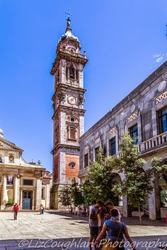 two people walking in front of a tall clock tower