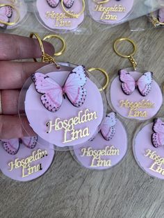 a hand holding a key chain with pink and white butterflies on it that say, hospedam land