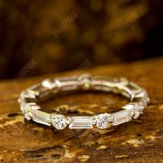 a diamond ring sitting on top of a piece of wood next to a stone wall