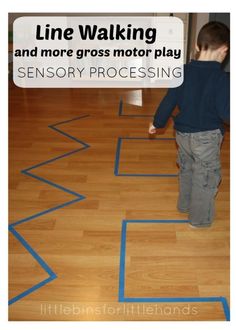 a young boy standing on top of a wooden floor next to a blue line drawing