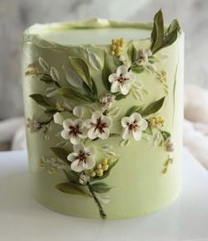 a close up of a cake with flowers and leaves on the frosted icing