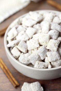 a white bowl filled with marshmallows next to cinnamon sticks