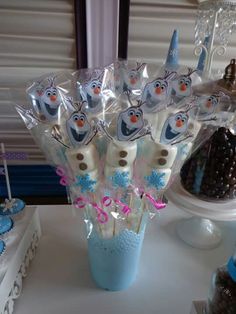 a table topped with cake pops covered in frosting and frozen world characters on top of them