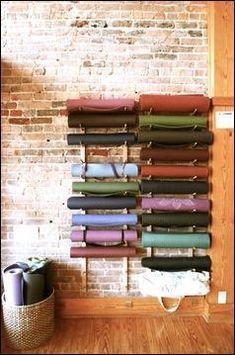 a wall mounted yoga mat rack in front of a brick wall