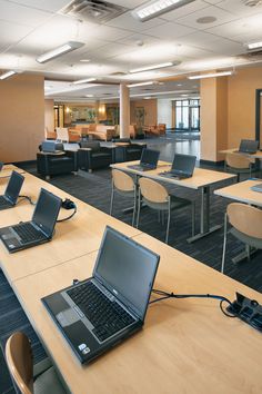 two laptops are sitting on the tables in an office setting with chairs and desks