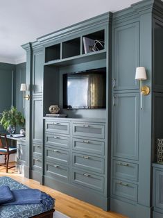 a living room with blue furniture and a flat screen tv mounted on the side of it