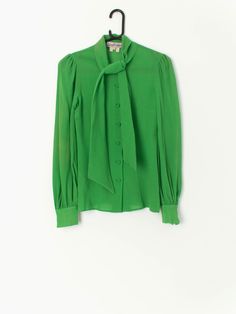 Vintage 70s Gina Fratini blouse with a tie front collar, long sleeves with button. In bright green. Would look lovely with some flared trousers or mini skirt.  Our recommended size: XXS  Label says: 10 Condition: Very good, tiny hole/pull in front (see last images, not colour accurate) Material: 100% wool Measurements in inches: Pit to pit: 15 Shoulders: 13.5 Front length: 24.5 Back length: 24 Sleeve length: 25 We've provided garment measurements and we recommend that you compare our measurement Fitted Tie Neck Blouse, Fitted Tie Neck Blouse With Button Closure, Fitted Tie Neck Blouse For Daywear, Classic Green Blouse For Work, Green Collared Blouse For Office, Classic Fitted Tie Neck Blouse, Spring Tie-neck Top With Button Closure, Chic Fitted Tie Neck Blouse, Spring Tie Neck Top With Button Closure