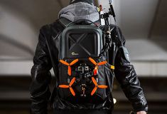 a man wearing a black jacket with an orange and grey back pack on his back