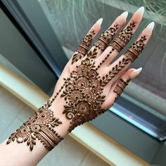 a woman's hand with henna tattoos on her arm and hands, showing the intricate