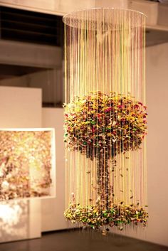 a sculpture made out of string and beads in a room with two paintings on the wall