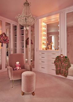 a pink room with a chair, mirror and chandelier in the corner that has a teddy bear on it