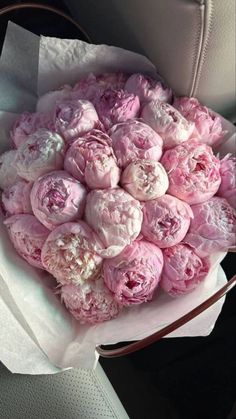 a bouquet of pink peonies sitting on top of a car seat