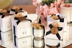 three small candles are sitting on a table next to two boxes with flowers in them