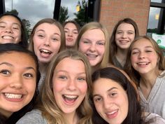 a group of young women standing next to each other in front of a brick building