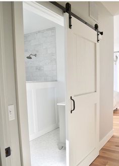 an open door leading to a bathroom with white walls and wood floors in the background