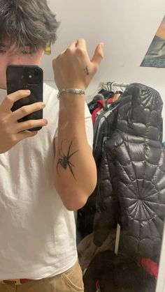 a person taking a selfie in front of a mirror with a spider tattoo on their arm