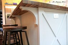 two wooden stools sitting in front of a counter top with a barn door on it