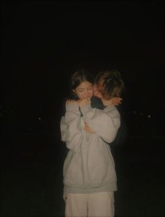 two young children are hugging each other in the dark, one is wearing a hoodie