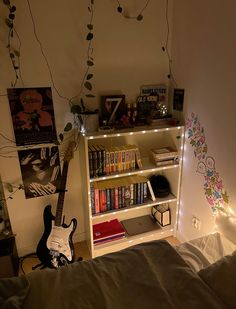 a bedroom with a book shelf and guitar on the bed