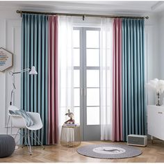 a living room with blue and pink curtains on the window sill, white chair and rug