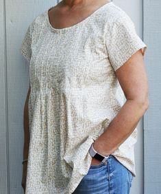 a woman standing in front of a white wall with her hands on her hips and smiling at the camera