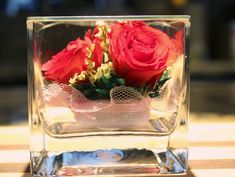 two red roses in a clear vase on a table