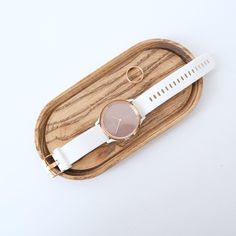 a white watch sitting on top of a wooden tray