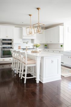 a large kitchen with white cabinets and wooden flooring, along with a center island