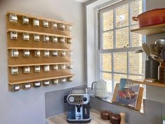 a coffee maker sitting on top of a wooden counter next to a wall mounted shelf filled with pots and pans