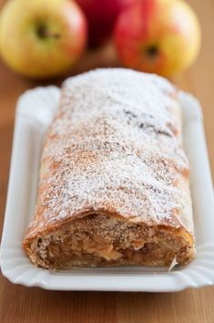 an apple pie on a white plate next to some apples