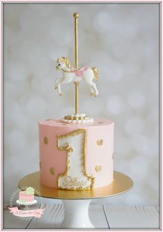 a pink and gold cake with a horse on top