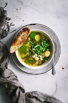 a bowl of soup with bread and peas