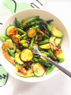 a white bowl filled with green vegetables on top of a table next to utensils