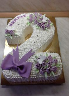 a cake shaped like the letter s with purple flowers on it and a large bow