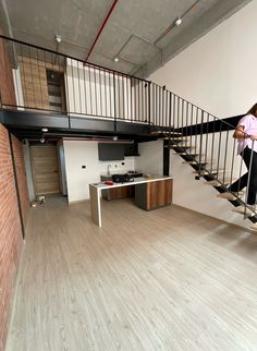 a woman is walking up the stairs in an empty room with wood floors and white walls