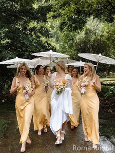 a group of bridesmaids walking down a path with umbrellas over their heads