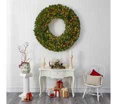 a christmas wreath on the wall next to a table with presents