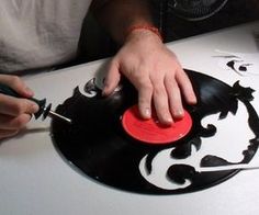 a person using a pair of scissors to cut out a vinyl record