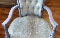 an upholstered chair sitting on top of a hard wood floor