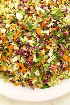 a white bowl filled with lots of veggies and salad dressing on top of a table